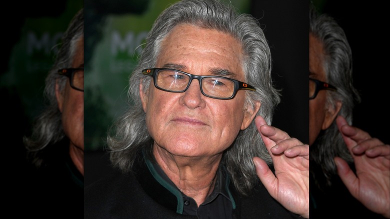 Kurt Russell gestures to his ear while on the red carpet.