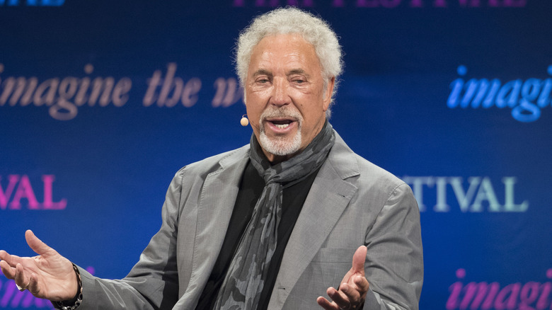 Tom Jones speaks animatedly on stage.