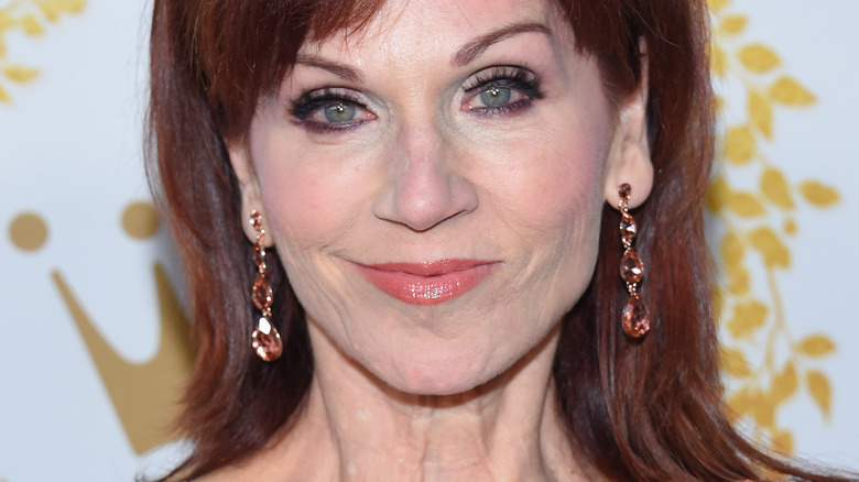 Marilu Henner wears jewel earrings and pink lipstick