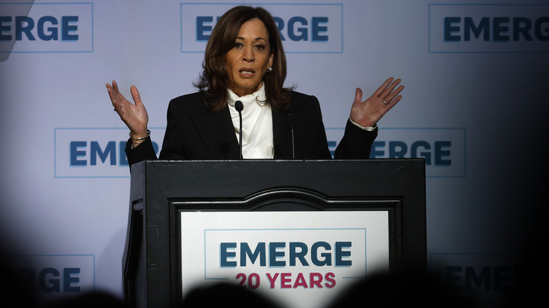 Kamala Harris behind a podium with her hands up