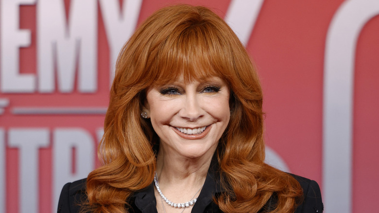 Reba McEntire posing in a jacket with a big smile