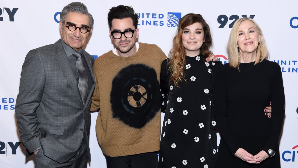 Eugene Levy, Dan Levy, Annnie Murphy, Catherine O'Hara smiling and embracing on a red carpet