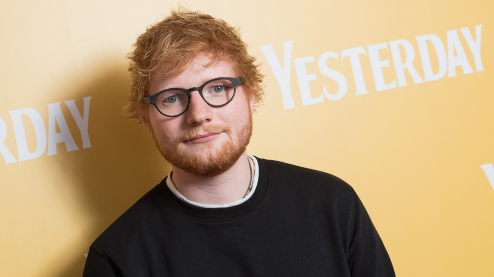 Ed Sheeran posing on the red carpet wearing glasses