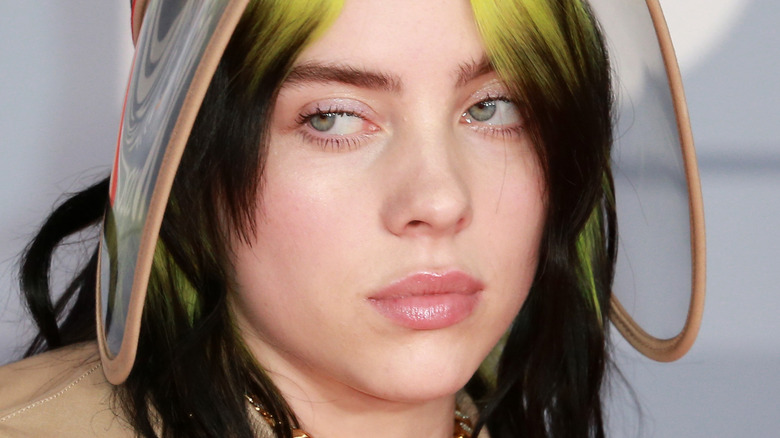 Billie Eilish with green hair and visor looking to side