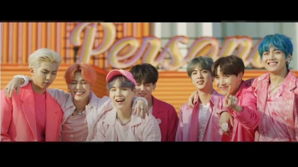 BTS smiling adjacent to one another in a screenshot from their music video for "Boy with Luv feat. Halsey"