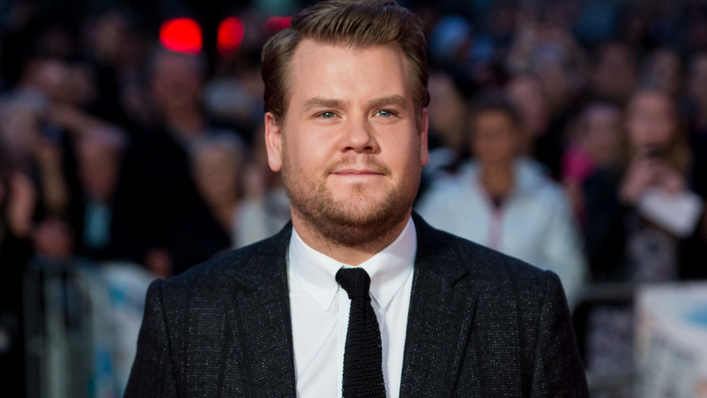 James Corden wearing a black suit and tie on the red carpet