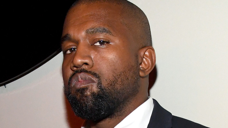 Kanye West wearing a suit with serious expression