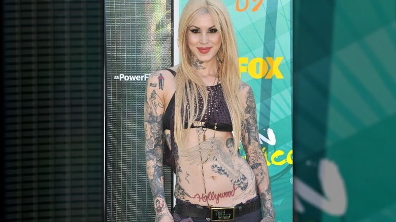 Kat Von D blonde hair posing in bikini top and jeans