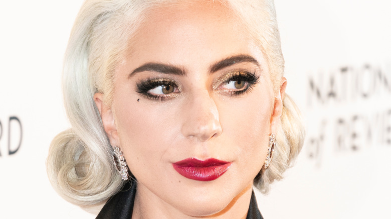 Lady Gaga with red lipstick and slight smile on the red carpet