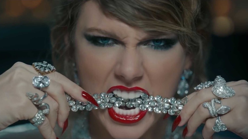 Taylor Swift biting down on a piece of diamond jewelry