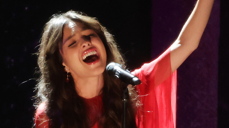 Olivia Rodrigo sings into a microphone on stage