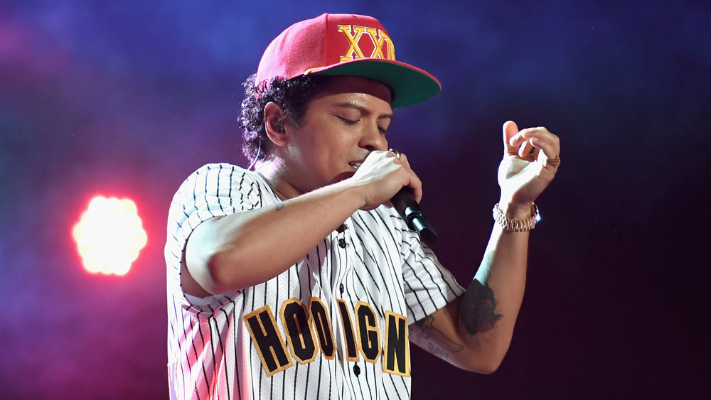 Bruno Mars wearing a baseball cap performing on stage