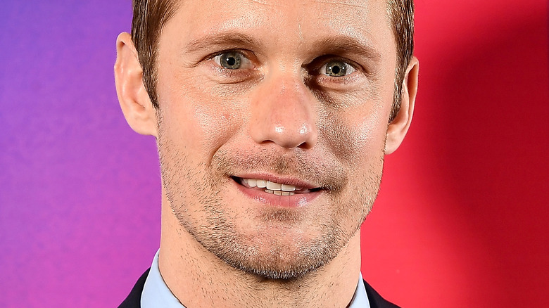 Alexander Skarsgård smiles against bright backdrop