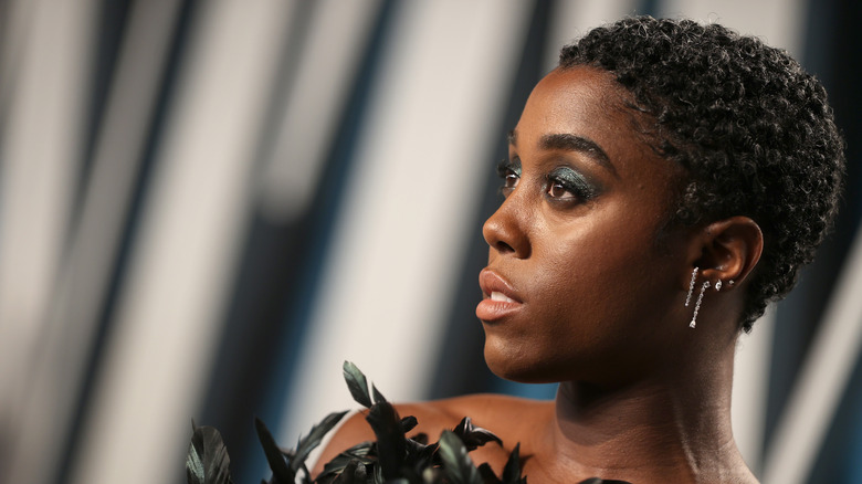 Lashana Lynch poses in a black feathery dress.