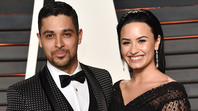 Wilmer Valderrama and Demi Lovato smiling on red carpet