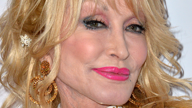 Dolly Parton wearing hot pink lip gloss and gold earrings