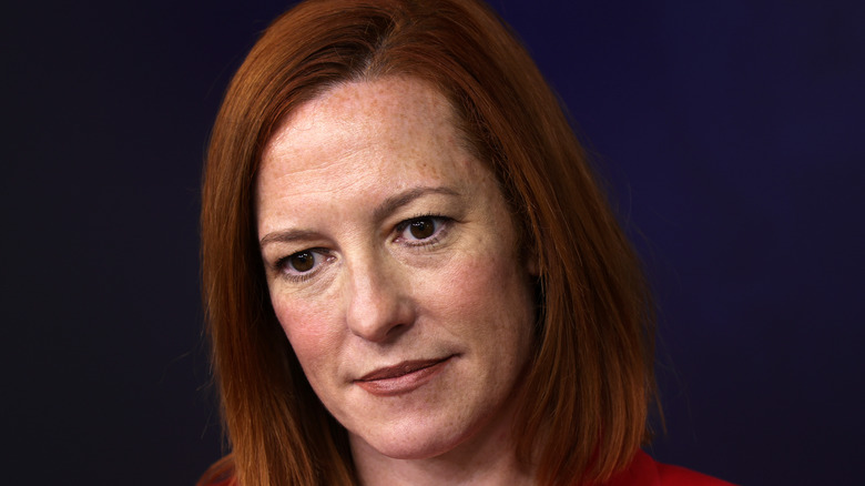 Jen Psaki, not smiling, looking at someone, wearing makeup, in a press briefing from March 2021