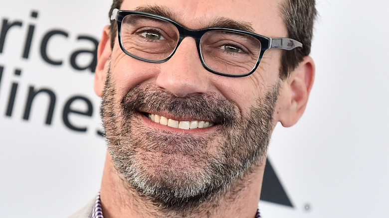 Jon Hamm smiles in black-frame glasses