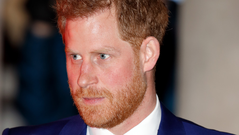 Prince Harry staring into the distance wearing a blue suit