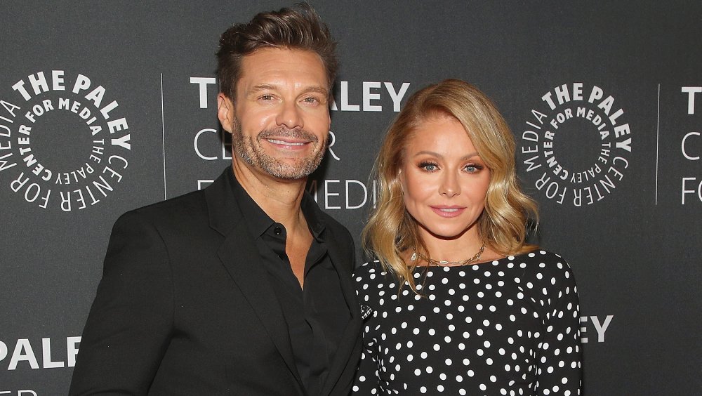 Ryan Seacrest and Kelly Ripa smiling while posing arm in arm