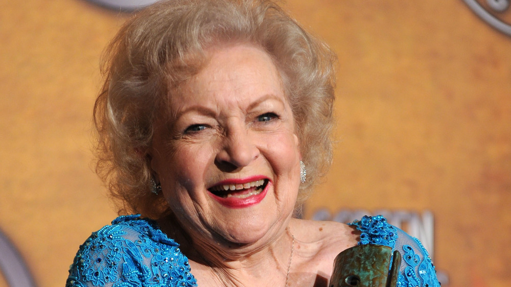 Betty White smiles excitely with an award in her hand