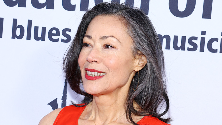 Ann Curry posing in front of a white background with blue lettering