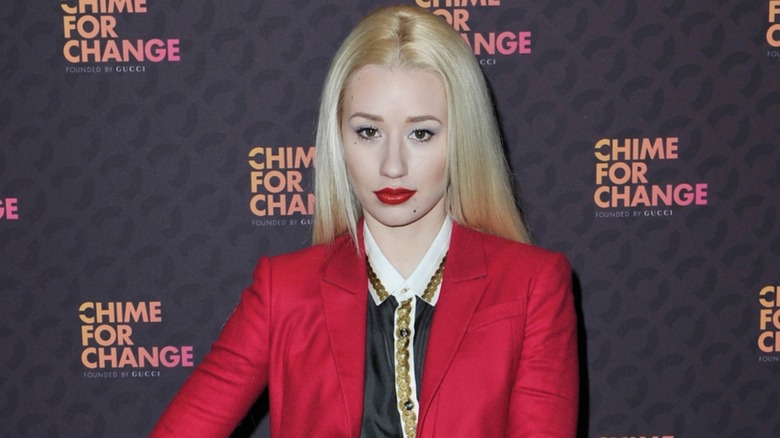 Dressed in a red suit and wearing red lipstick, Iggy Azalea stares directly into the camera.
