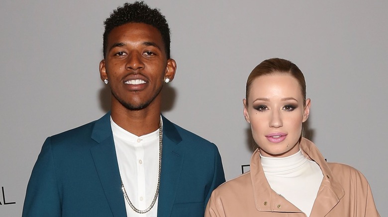 Iggy Azalea and Nick Young stand next to each other and smile while staring at the camera.
