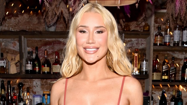 Iggy Azalea sports a revealing pink number while all smiles against a bar background.