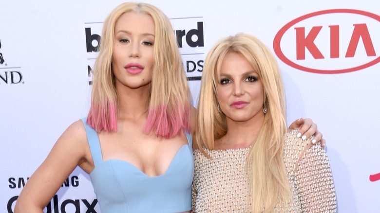 Iggy Azalea standing next to Britney Spears with one arm wrapped around the pop star's shoulder.