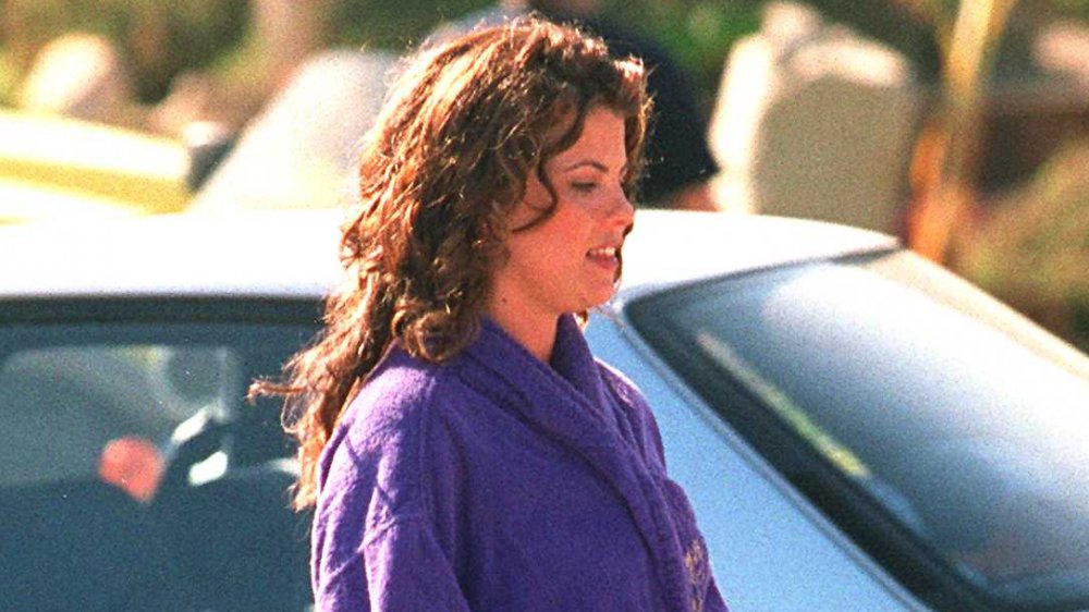 Yasmine Bleeth walking outside, wearing a purple bathrobe over her Baywatch wardrobe