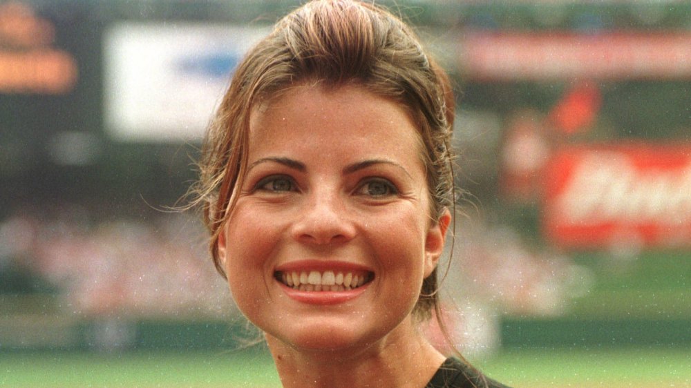 Yasmine Bleeth smiling big, wearing a black top, with her hair pulled back at an outdoor event