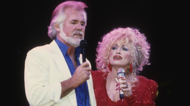 Dressed in a shimmery red outfit, Dolly Parton belts out a tune as she gazes at Kenny Rogers.
