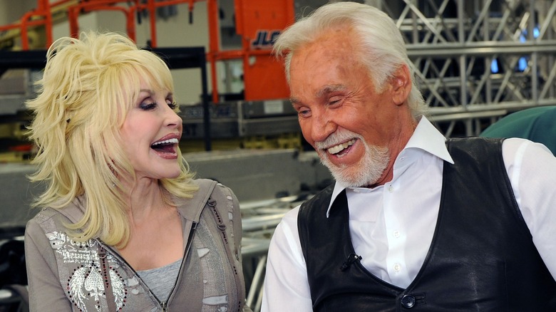 Dolly Parton laughs hard while gazing down at an amused Kenny Rogers.