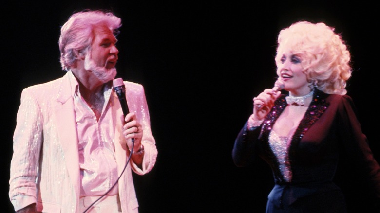 Dressed in shimmery outfits, Dolly Parton and Kenny Rogers sing while looking into each other's eyes.