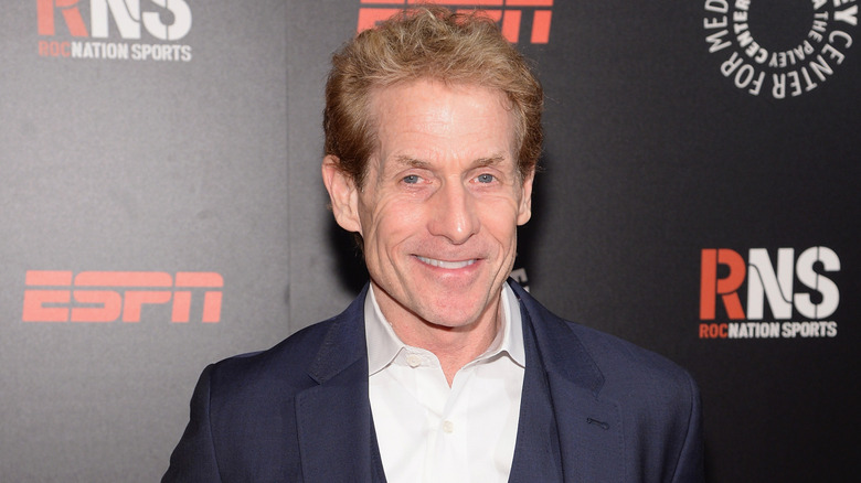 Skip Bayless poses in a blue jacket and white collared shirt.