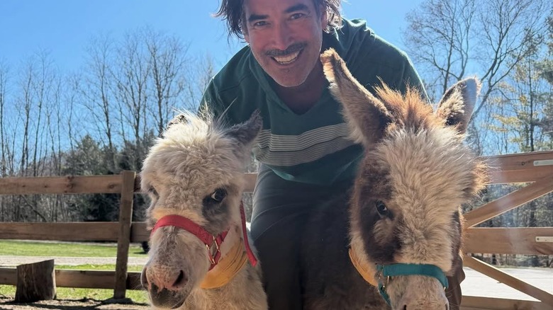 Carter Oosterhouse posing alongside two mini donkeys