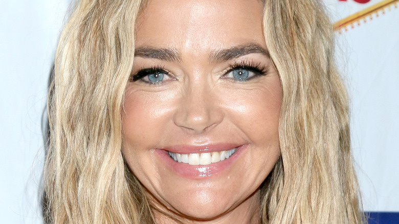 Denise Richards smiles in a yellow top