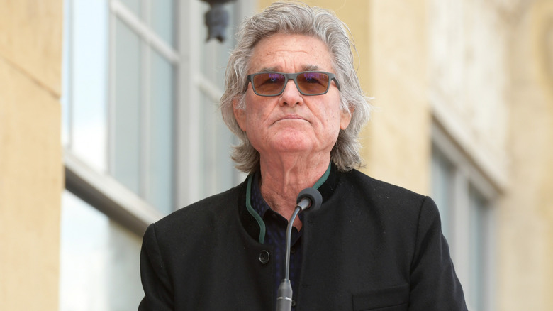 Kurt Russell standing at a microphone