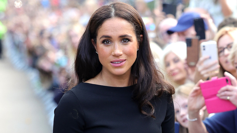 Meghan Markle wearing a black top next to a crowd