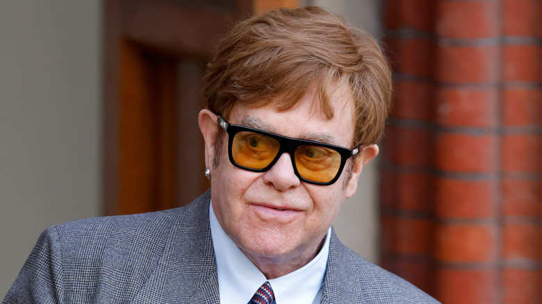 Elton John walks wearing suit