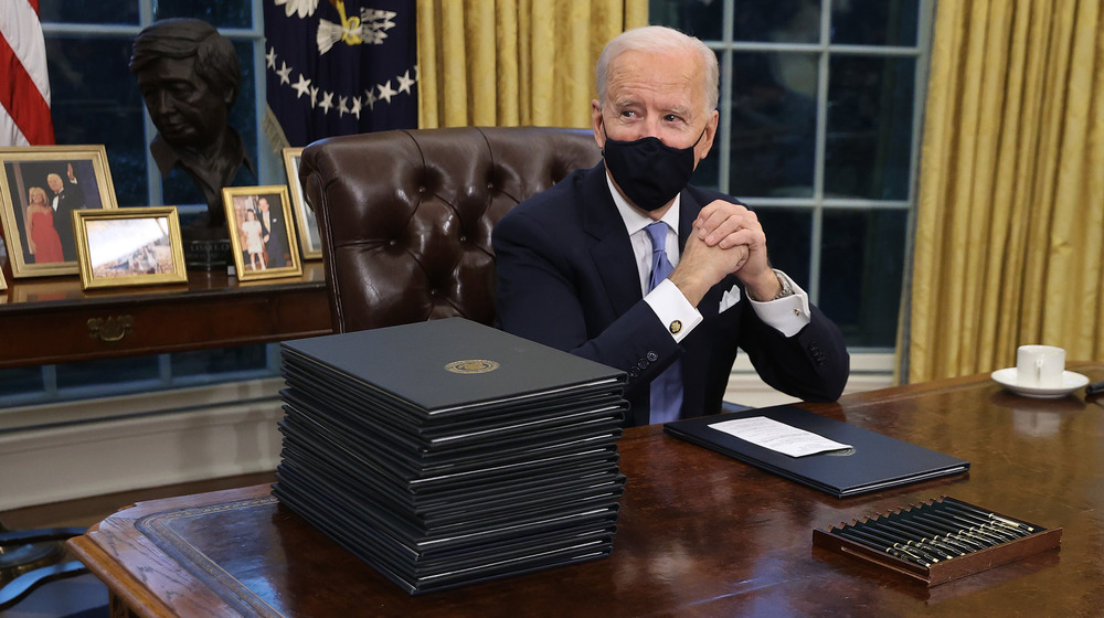 Joe Biden sitting at the oval office after it was redecorated