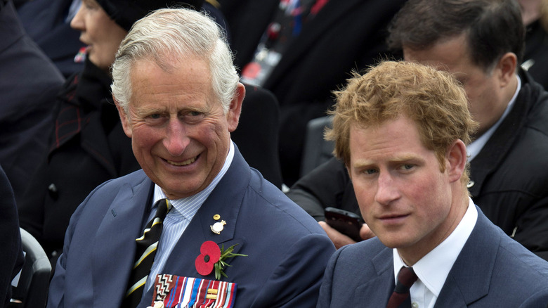 Prince Charles grinning beside Prince Harry