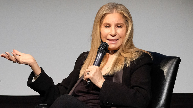 Barbra Streisand with microphone in hand, speaking