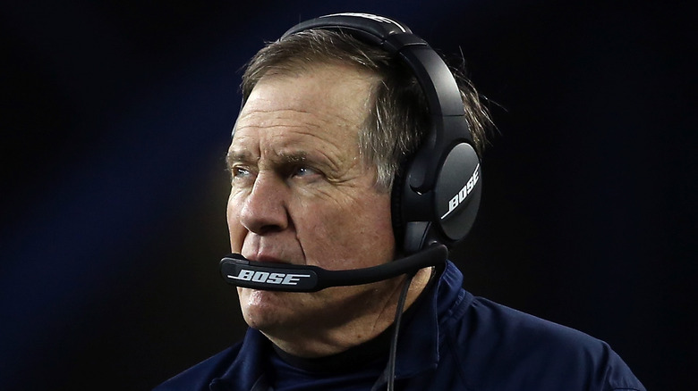 Bill Belichick speaking into his headset on the field