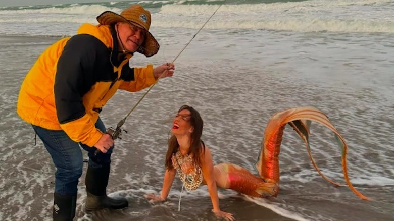 Bill Belichick with a fishing rod catching girlfriend Jordon Hudson, dressed like a mermaid