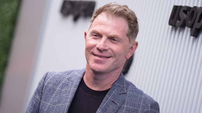 A slanted image of Bobby Flay in a gray suit