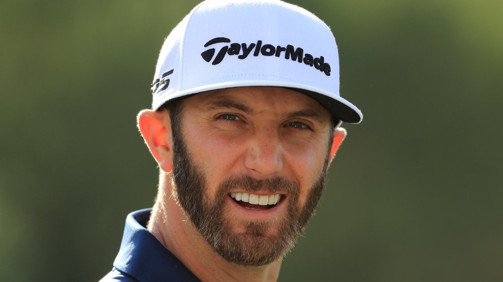 Dustin Johnson in a white cap, smiling during a match