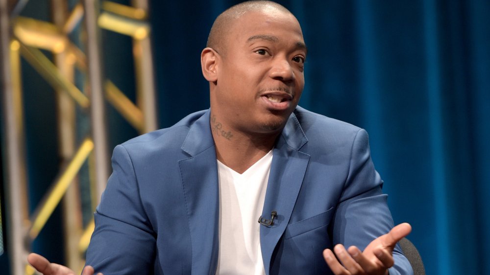 Ja Rule in a blue blazer and white v-neck t-shirt, speaking and shrugging