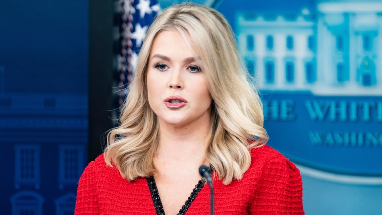 Karoline Leavitt speaks into the microphone on a podium at the White House press briefing room.